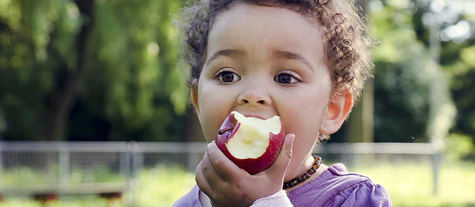 A child eats an apple outside.