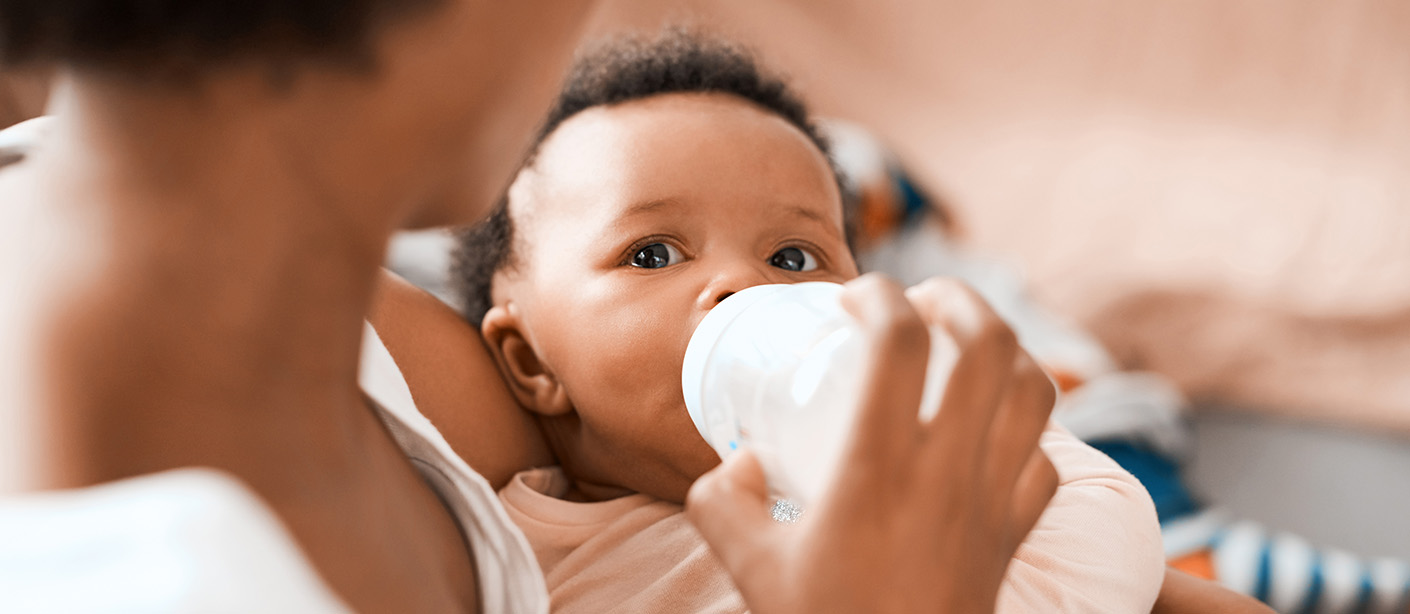 A mother cradling a baby while feeding a bottle