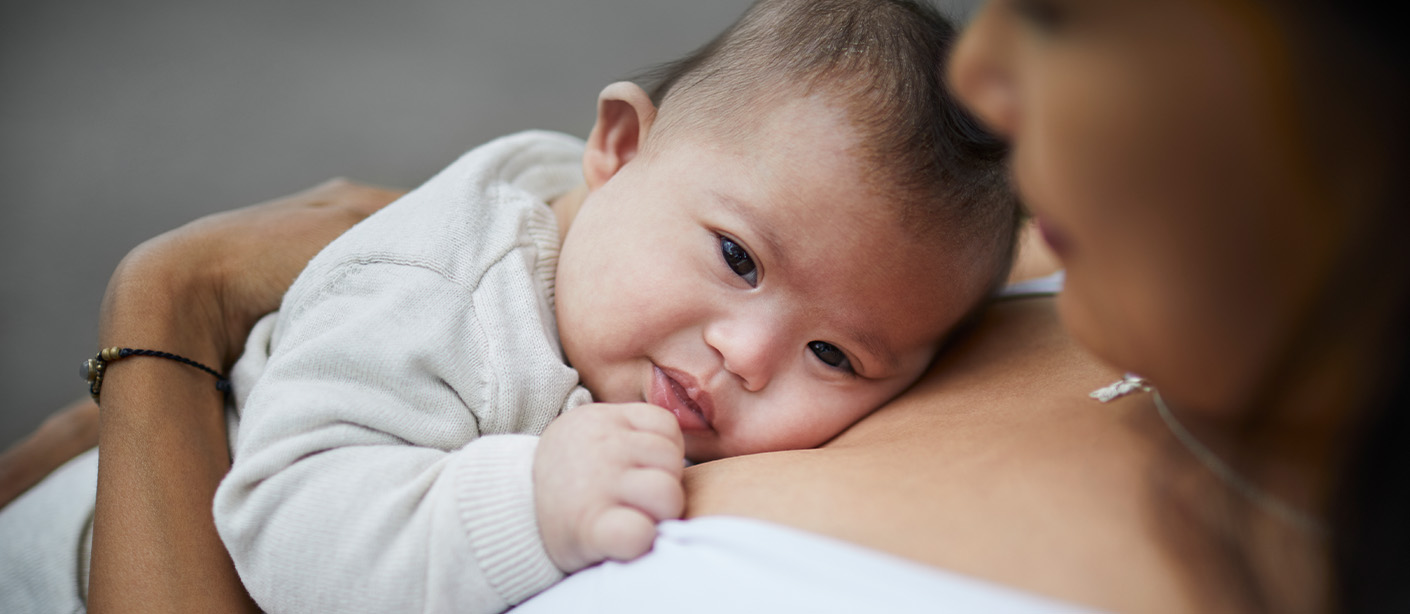 A baby lays on their mother's chest