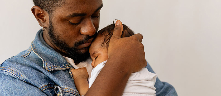 A father cradling a newborn baby